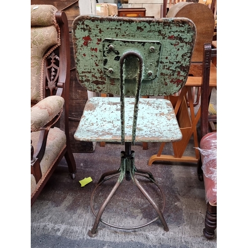 435 - Star Lot : A Vintage industrial metal swivel machinists chair with distressed green paint from the e... 