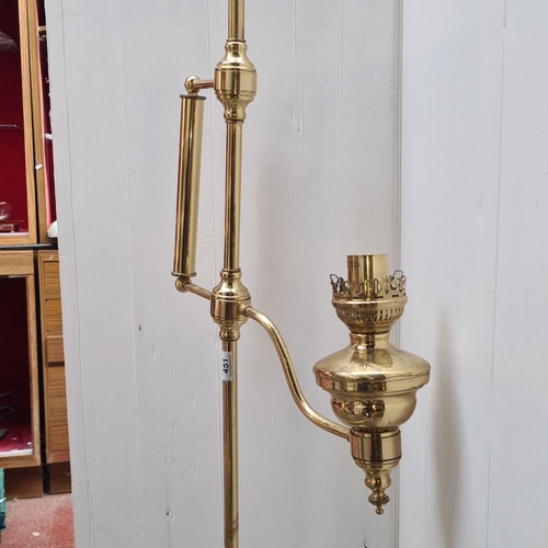 451 - Brass floor lamp, in the Edwardian style with an adjustable arm and electric fitting. It features cl... 