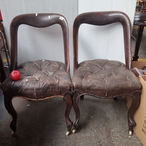 478 - Pair of Victorian balloon-back chairs with tufted leather seats, featuring carved mahogany frames an... 