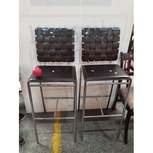 483 - Set of two tall Modern bar stools. Feature chrome frames with woven black leather backrests and seat... 