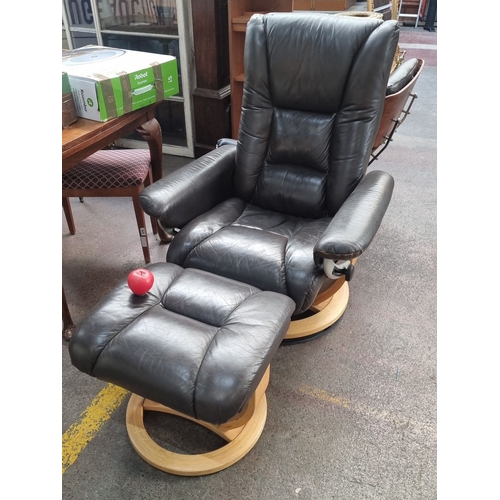 489 - Star Lot : An excellent condition Contemporary black leather recliner with matching ottoman, featuri... 