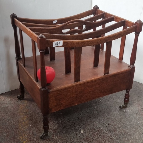 494 - A mahogany  Canterbury from the Victorian period with turned legs and casters, featuring open slatte... 