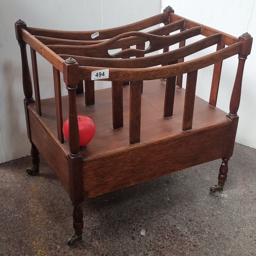 494 - A mahogany  Canterbury from the Victorian period with turned legs and casters, featuring open slatte... 