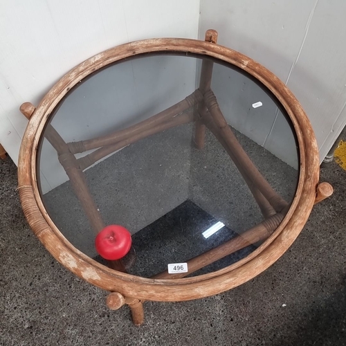 496 - Round rattan coffee table with glass top, featuring rustic, natural wood finish and unique woven det... 