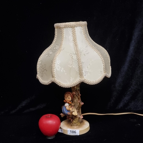 186 - A beautiful West German Hummel table lamp fitted with a satin shade and depicting a young girl climb... 