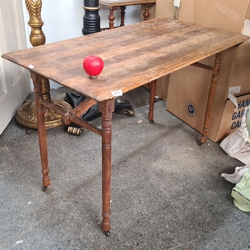 879 - Antique wooden folding table with turned legs and caster wheels. Natural wood finish with visible gr... 