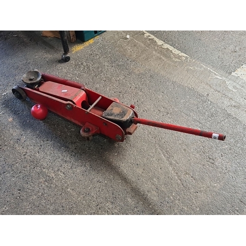 900 - Vintage red hydraulic floor jack with lifting handle, steel construction, manual operation.