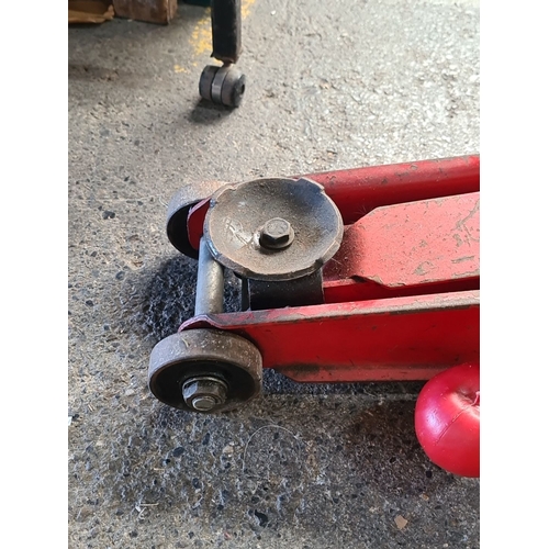 900 - Vintage red hydraulic floor jack with lifting handle, steel construction, manual operation.