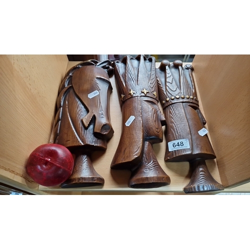 648 - Three hand-carved wooden knight chess pieces with felted bases, accompanied by a red game piece.