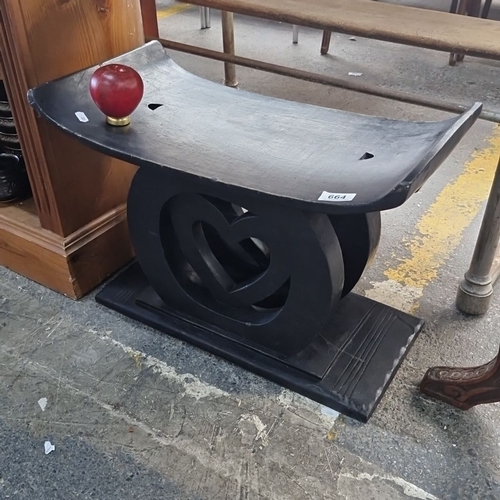 664 - An Ashanti  stool made from ebonized wood, featuring curved seat and heart-shaped cutout design in t... 