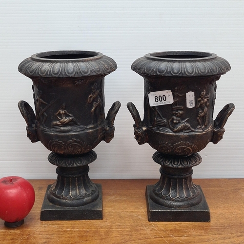 800 - A pair of mini Victorian-style heavy cast iron urns with detailed classical reliefs. Features ornate... 