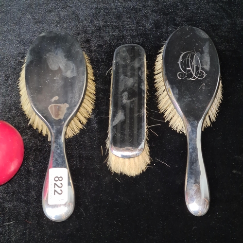 822 - A lot of three sterling silver case brushes including two hair brushes and one clothes brush. All ha... 