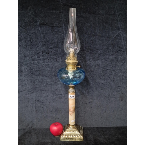 829 - A striking early 20th Century oil lamp featuring a striking blue glass reservoir and original chimne... 