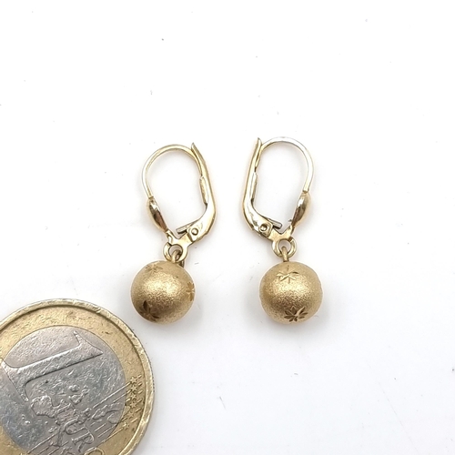 627 - A very nice pair of 14 carat gold drop earrings with sphere pendant that feature delicate engravings... 