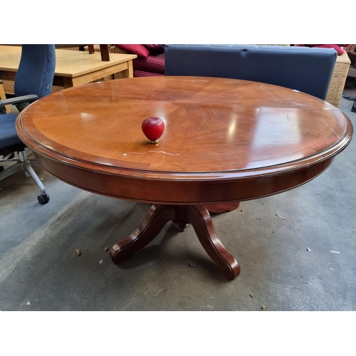 939 - A solid mahogany round dining table featuring a pedestal base. Detailed craftsmanship with elegant l... 