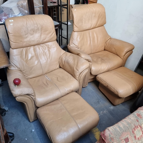 941 - Two tan leather chairs with reclining headrests matching footstools. Features padded headrests and a... 