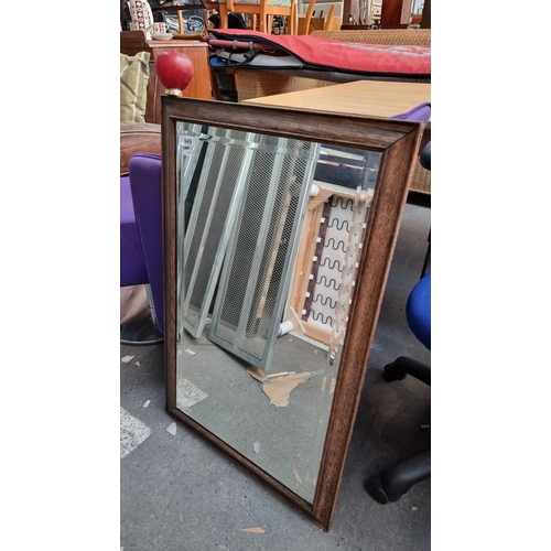 949 - A handsome mid century bevelled wall mirror housed in a wooden oak frame.