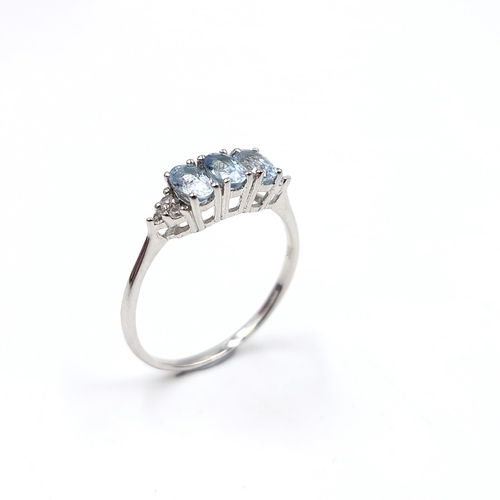 434 - A three stone aquamarine ring set with diamond accents mounted in sterling silver. Size - R. Weight ... 