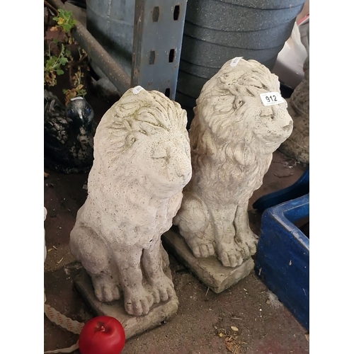 912 - A Pair of stone lion garden statues, showing intricate detailing and weathered patina.