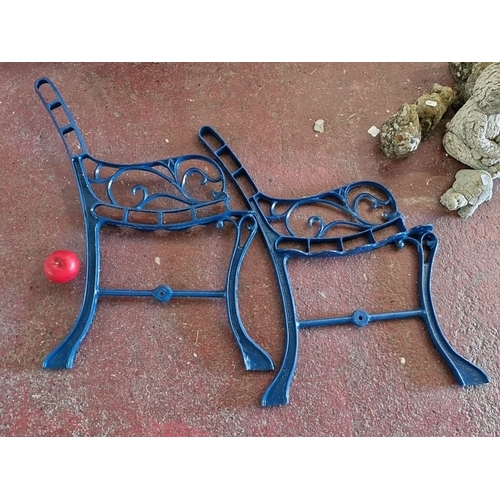 914 - Pair of ornate blue cast iron bench ends featuring scrollwork design.