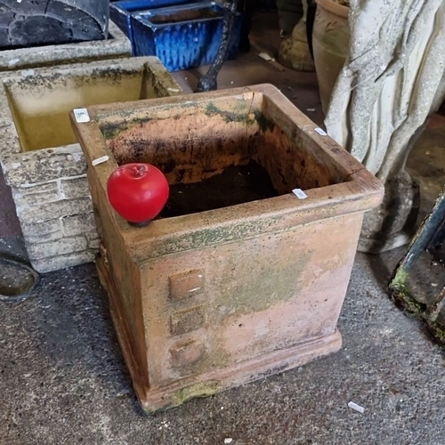 921 - A large Square terracotta garden planter with weathered patina, featuring four raised square decorat... 