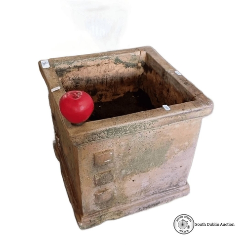 921 - A large Square terracotta garden planter with weathered patina, featuring four raised square decorat... 