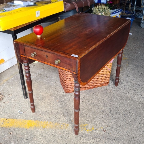 938 - A 19th-century drop-leaf mahogany table with one drawer and brass pulls, featuring elegant turned le... 