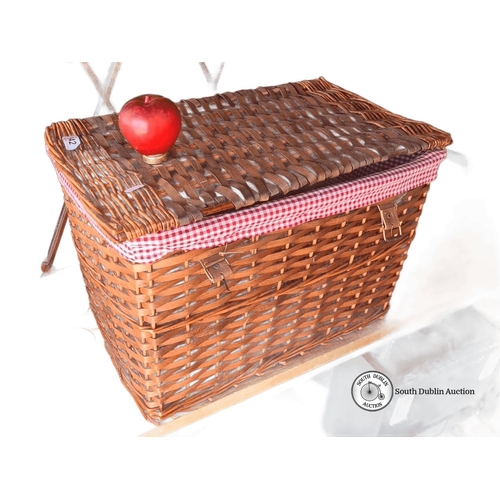 942 - A large Woven wicker picnic basket with hinged lid, dual brass clasps, and red gingham fabric lining... 