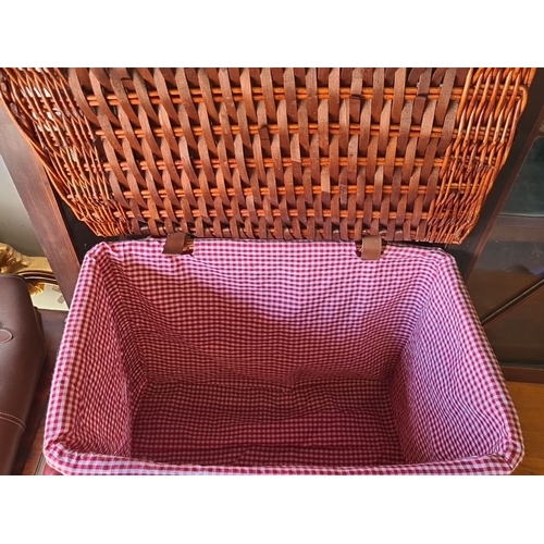 942 - A large Woven wicker picnic basket with hinged lid, dual brass clasps, and red gingham fabric lining... 