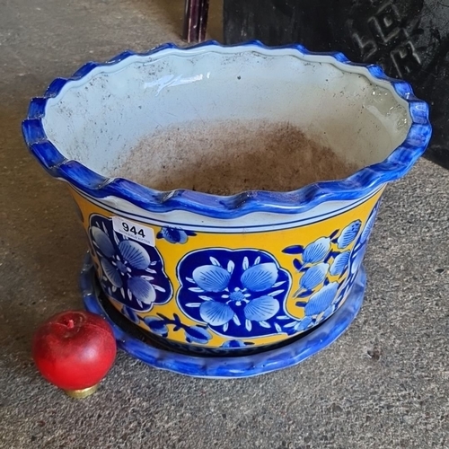 944 - A Hand-painted ceramic planter with floral blue and yellow design, accompanied by a matching base tr... 