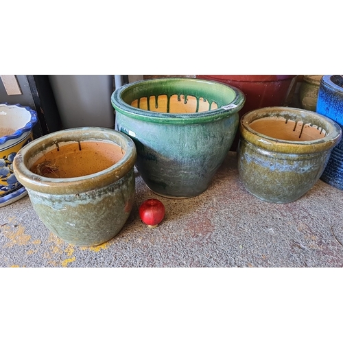 945 - A Set of three glazed ceramic planters, featuring earthy green tones and a rustic drip effect.