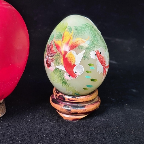 579 - A mini hand painted jade egg sat upon a wooden stand.