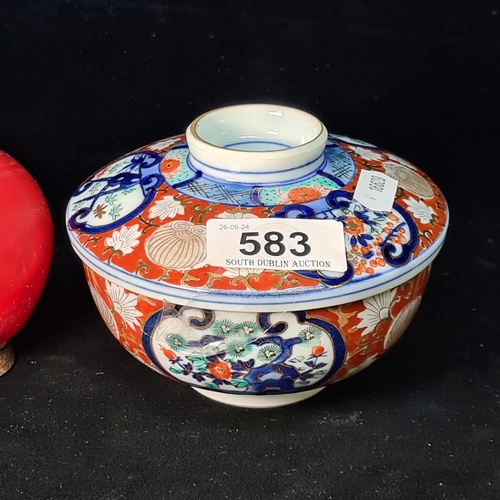 583 - A beautiful Japanese Imari lidded dish, hand painted with traditional scenery and motifs in tones of... 