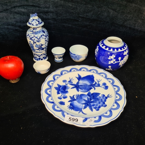 599 - A collection of oriental blue and white patterned porcelain items including two sake cups and a urn ... 