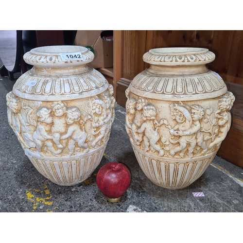 1042 - Pair of neoclassical style terracotta urns featuring cherub relief decoration.