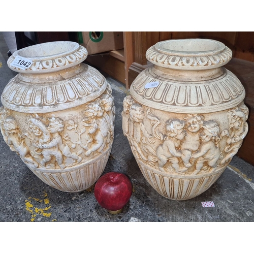 1042 - Pair of neoclassical style terracotta urns featuring cherub relief decoration.