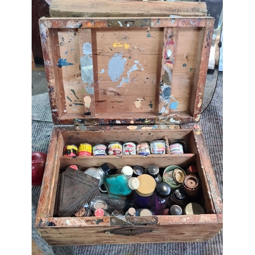 1057 - A vintage wooden artist's paint box with assorted vintage paint bottles and tools, including enamel ... 