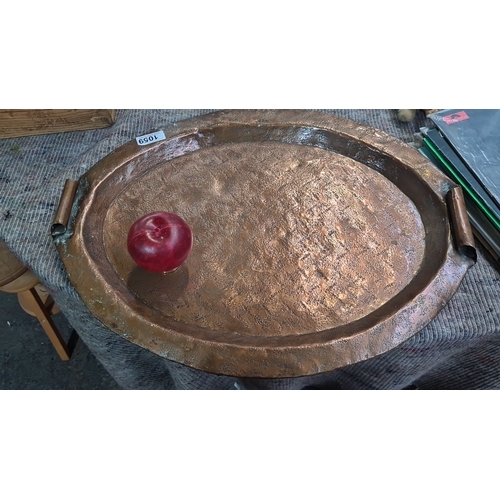 1059 - A Vintage hand-hammered copper tray with rolled-edge handles, showcasing a rustic textured finish.