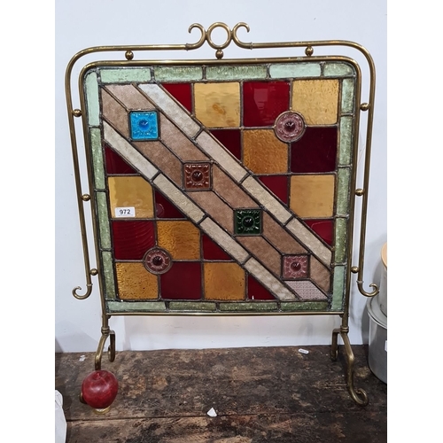 972 - Star lot :A Brass-framed stained glass fire screen, featuring a geometric pattern with squares and f... 