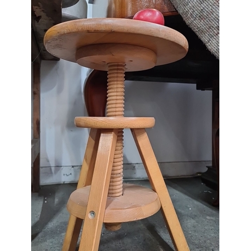 974 - A Wooden adjustable-height potters stool with screw mechanism and three legs. Light-colored finish, ... 