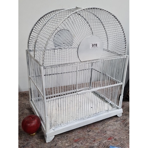 978 - White-painted metal birdcage with an arched top, featuring intersecting wire bars and a door on one ... 