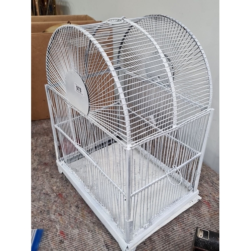 978 - White-painted metal birdcage with an arched top, featuring intersecting wire bars and a door on one ... 