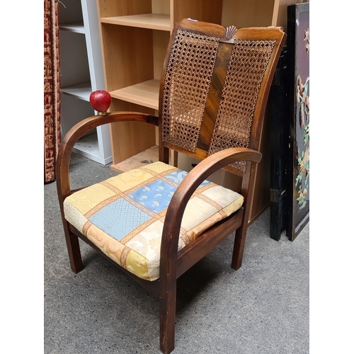 980 - Vintage wooden armchair with woven cane backrest and patterned fabric cushion. The chair includes cu... 