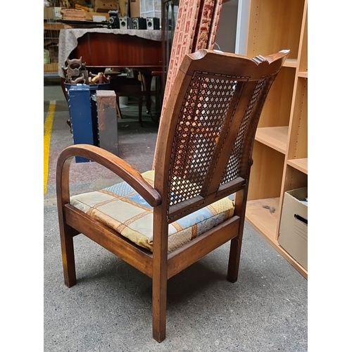 980 - Vintage wooden armchair with woven cane backrest and patterned fabric cushion. The chair includes cu... 