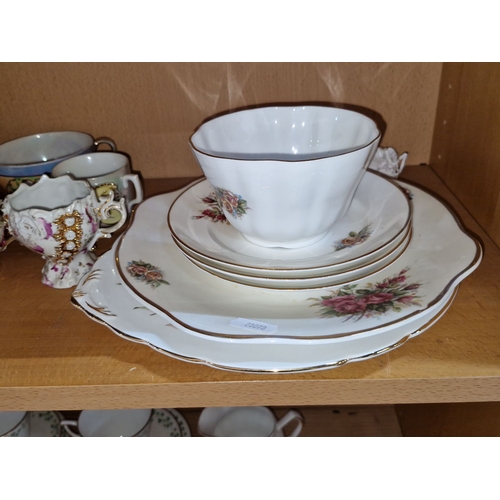 1142 - Assorted china teacups, saucers, and plates with floral designs. Decorative pink glass pitcher. Two ... 