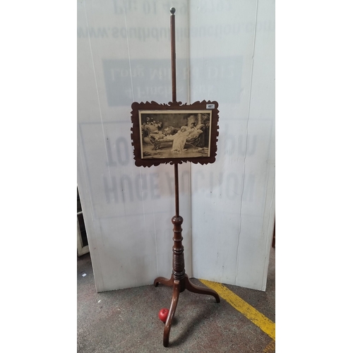 1165 - Victorian mahogany adjustable pole screen with an intricately carved frame displaying a black and wh... 