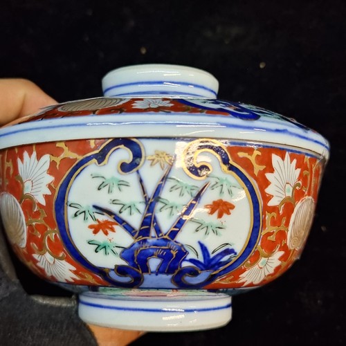 583 - A beautiful Japanese Imari lidded dish, hand painted with traditional scenery and motifs in tones of... 