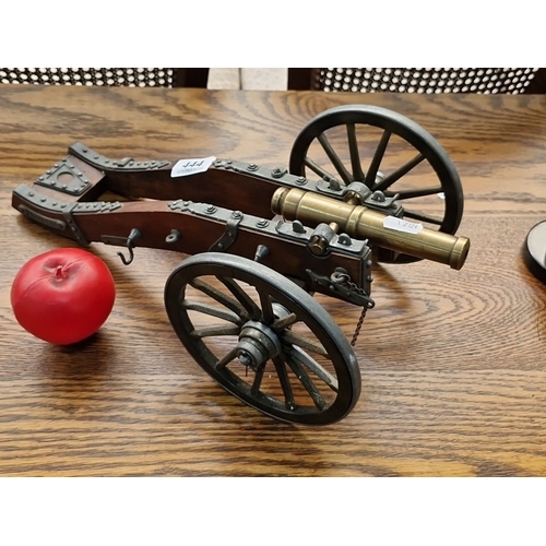 444 - A heavy vintage brass and wood miniature cannon on wheels, measuring approximately 15 inches in leng... 