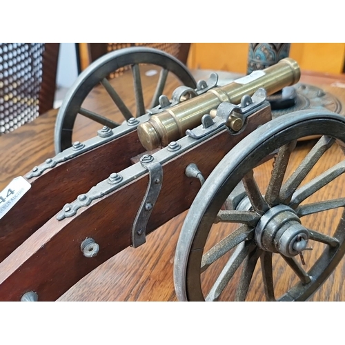 444 - A heavy vintage brass and wood miniature cannon on wheels, measuring approximately 15 inches in leng... 