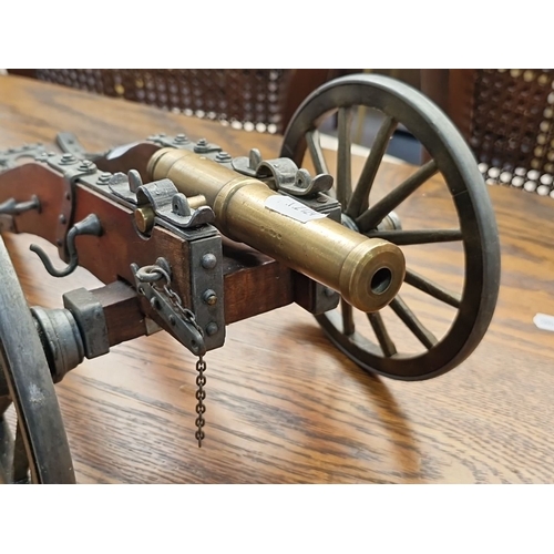 444 - A heavy vintage brass and wood miniature cannon on wheels, measuring approximately 15 inches in leng... 